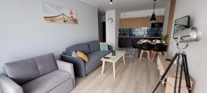 a living room with a blue couch and a kitchen at Marina Dziwnów Apartment in Dziwnów