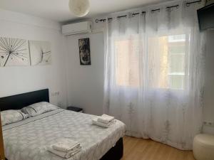 Schlafzimmer mit einem Bett und einem Fenster mit weißen Vorhängen in der Unterkunft Duplex a 3 minutos de playa de la victoria Cadiz in Cádiz