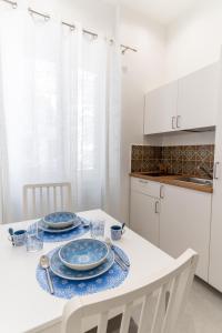 a white kitchen with a table with blue dishes on it at Nena Sweet Home in Palermo