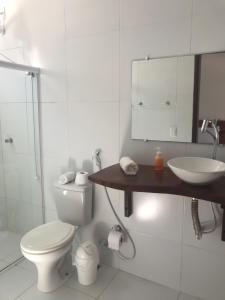 a white bathroom with a toilet and a sink at Pousada Recanto Pontal de Maracaipe in Porto De Galinhas