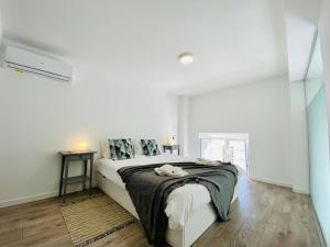 a white bedroom with a bed with a blanket on it at Tia Anica House I - apartment with terrace in central Fuseta beach village in Fuzeta