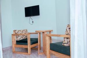 Zimmer mit einem Tisch, einem TV und einem Stuhl in der Unterkunft WestWay Luxury Suites in Mbarara