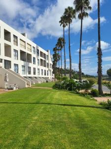 a large lawn in front of a building with palm trees at 13 at Santos in Mossel Bay