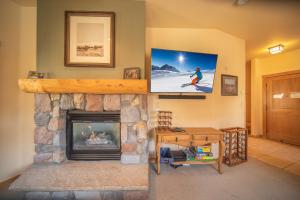 a living room with a fireplace and a tv on the wall at Arapahoe Lodge 8120 in Keystone