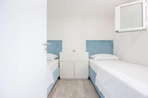 two beds in a room with white and blue at Perina Haven - Island Vis Beachfront in Rogačić