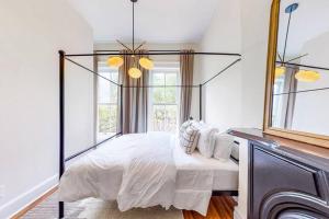 a bedroom with a canopy bed with white sheets and pillows at Luxury 8 Bed/4 Ba NuLu Home Private yard/parking in Louisville