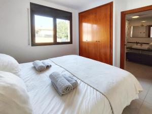 una camera da letto con un grande letto bianco con asciugamani di Casa con piscina en L'Estartit a Girona