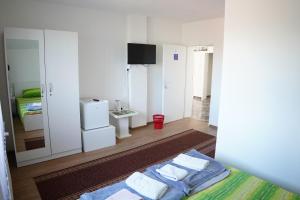 Rooms Busujok في كلادوفو: غرفة بيضاء فيها سرير وتلفزيون