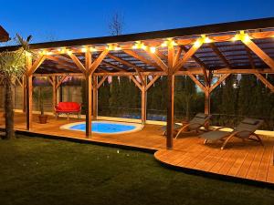 a wooden deck with a pool and a pergola at Morze Domków Wellness & Spa in Dziwnówek