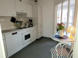 a kitchen with white cabinets and a table with a vase of flowers at Heimathafen Hohwacht in Hohwacht