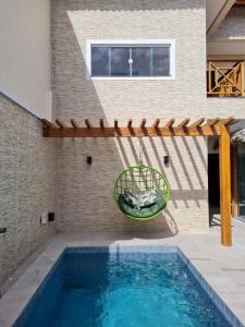 a swimming pool with a swing in front of a house at Casa com Píer à Beira do Rio Preguiças em Condomínio Fechado in Barreirinhas