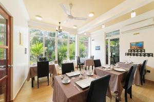 a dining room with tables and chairs and windows at Sevinex Inn in Feridhoo