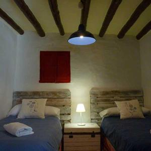 sypialnia z 2 łóżkami i lampką na stole w obiekcie Apartamentos Casa Mata w mieście Colungo