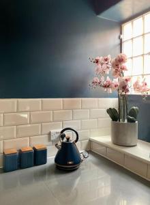 a tea kettle sitting on a counter with a vase of flowers at Hurdley House-Georgian Town House in Montgomery