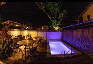 a patio with a table and a swimming pool at night at Flat Vila Taipu in Marau