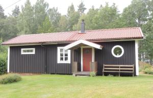 una pequeña casa negra con una puerta roja en Holiday Home Vrigstad with Lake View 02 en Vrigstad