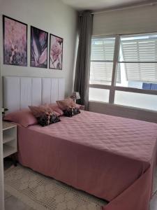 una camera da letto con un grande letto rosa con finestra di Praia do Tombo a Guarujá
