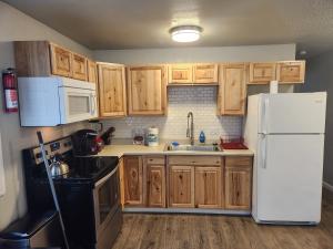 a kitchen with wooden cabinets and a white refrigerator at Nightshade BnB in Anchorage
