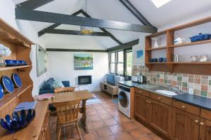 a kitchen with wooden cabinets and a table and a sink at Cosy cottage in the beautiful Lamorna Valley - walk to the pub & sea in Paul