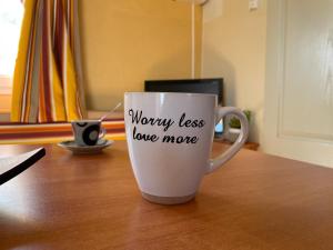 a coffee cup with the words worry less love more written on it at Chalet-home familiar "CAL DENVER" "Pet friendly" in Sant Carles de la Ràpita