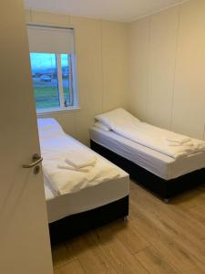 twee bedden in een kleine kamer met een raam bij Ghost Town Guest House 10 min from Airport in Hafnir