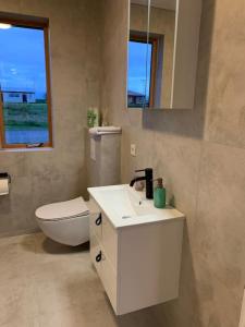 een badkamer met een wastafel, een toilet en een spiegel bij Ghost Town Guest House 10 min from Airport in Hafnir