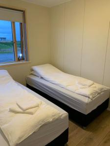 two twin beds in a room with a window at Ghost Town Guest House 10 min from Airport in Hafnir