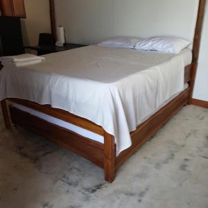 Bett mit einem Holzrahmen und einem weißen Laken in der Unterkunft Suite Casa PALUM Studio Apartment in Palomino