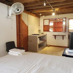 a room with a bed and a kitchen with a fan at Suite Casa PALUM Studio Apartment in Palomino