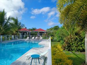 uma piscina com mesa, cadeiras e árvores em Hôtel & Villa Le Cocotel em Saint-François