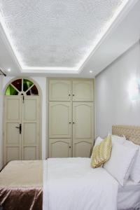 a bedroom with a bed and two white cabinets at DAR Riad Jomana in Marrakech