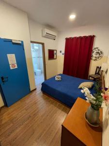 - une chambre avec un lit bleu et un rideau rouge dans l'établissement Marco Polo Party Hostel, à San Ġiljan