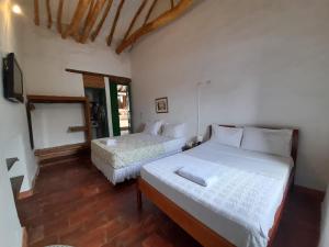 1 dormitorio con 2 camas y TV de pantalla plana en Posada Sueños de Antonio en Barichara