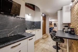 a kitchen with white cabinets and a black counter top at Oliviero - Piazza Navona Apartment in Rome