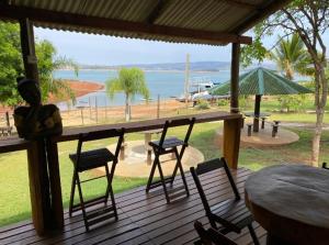 a table and chairs on a deck with a view of the water at Pousada Espelho D'Água Capitólio in Capitólio