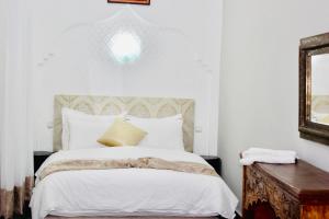 a bedroom with a large white bed with a mirror at DAR Riad Jomana in Marrakech