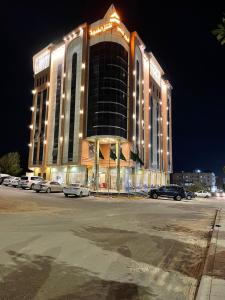 un gran edificio con coches estacionados en un estacionamiento en السهم الذهبي للشقق المخدومة en Taif