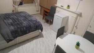 a bedroom with a bed and two tables and a refrigerator at Spacious Room near Manchester City Centre in Manchester