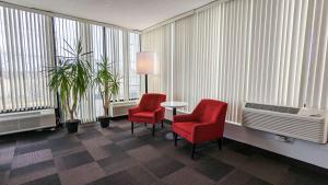 une pièce avec deux chaises rouges, une table et des fenêtres dans l'établissement Motel 6-Framingham, MA - Boston West, à Framingham