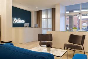 une salle d'attente avec un canapé bleu et des chaises dans l'établissement Radisson Hotel Ferrara, à Ferrare