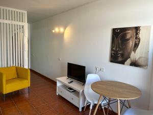 a living room with a table and a tv and a chair at Practical and cozy apartment in southern Arona in Arona