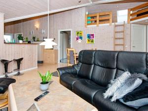 a living room with a black leather couch and a table at 6 person holiday home in Hemmet in Hemmet