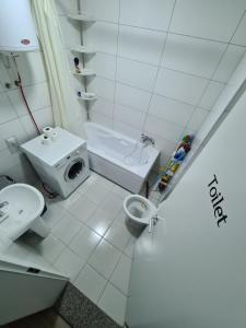 a white bathroom with a toilet and a sink at Daily Apartment Prishtina in Pristina