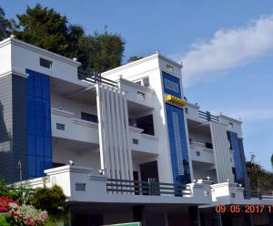 ein weißes Gebäude mit blauen Fenstern an der Seite in der Unterkunft Pinehill Suits in Udagamandalam