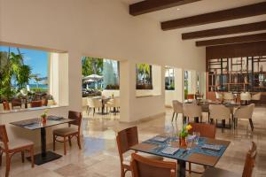 um restaurante com mesas, cadeiras e janelas em Dreams Sands Cancun Resort & Spa em Cancún