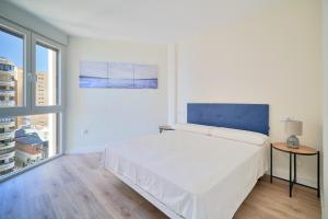 biała sypialnia z dużym łóżkiem i oknem w obiekcie Impresionante apartamento en Playa de la Malagueta w Maladze +10 zdjęć