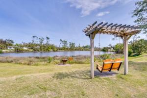 a bench under a pergola next to a lake at Lovely Panama City Cottage Walk to Bayside Beach! in Panama City