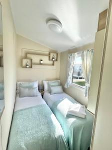 twee bedden in een kleine kamer met een raam bij Trecco bay caravan hire 4 bedrooms sleeps 10 in Porthcawl