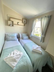 Duas camas num pequeno quarto com uma janela em Trecco bay caravan hire 4 bedrooms sleeps 10 em Porthcawl