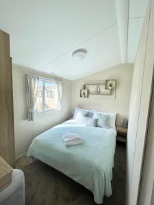 een witte slaapkamer met een groot bed met witte kussens bij Trecco bay caravan hire 4 bedrooms sleeps 10 in Porthcawl
